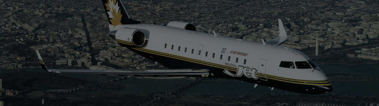 MHIRJ regional jet flying over a city
